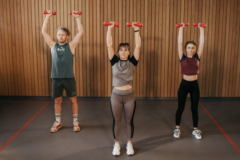 участники занятия body sculpt выполняют выпады с гантелями на степ-платформах