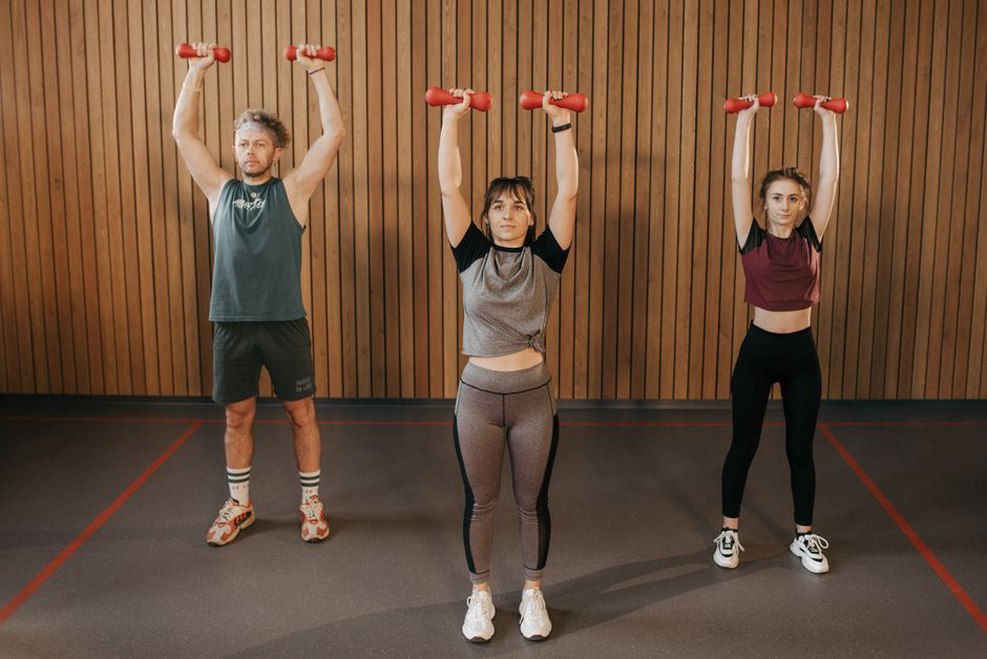 участники занятия body sculpt выполняют выпады с гантелями на степ-платформах